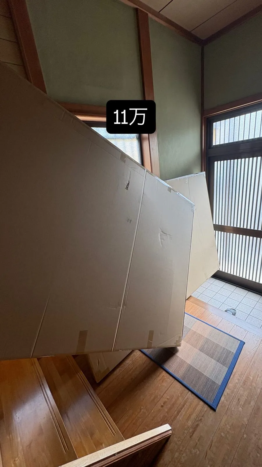 玄関に届いたダンボールと「11万」の文字